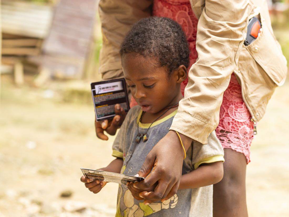 A child holding a Gospel tract received during the Dompim outreach